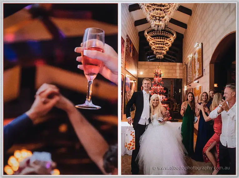 Bride and groom walk a chandelier-lit corridor past a red-lit tree as guests applaud