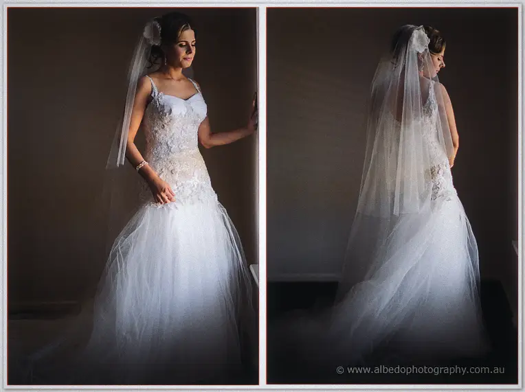 Veiled Elena in her tulle mermaid gown, facing camera then turned into the dim stairwell light