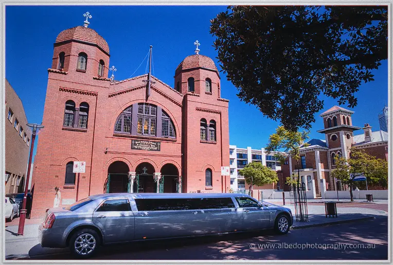 Silver stretch limousine parked before the red-brick domes of the Northbridge cathedral