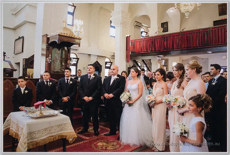 James, Elena, groomsmen and blush bridesmaids line up before the carved wooden pulpit