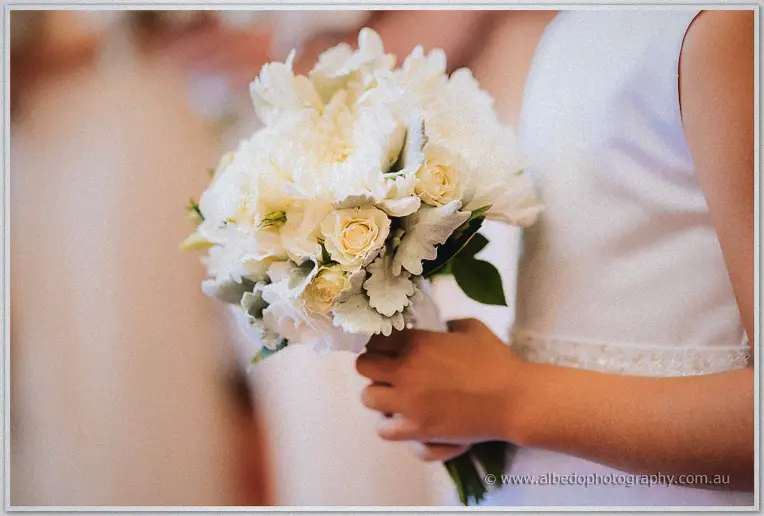 Close-up of white roses and dusty miller in the flower girl's small bouquet