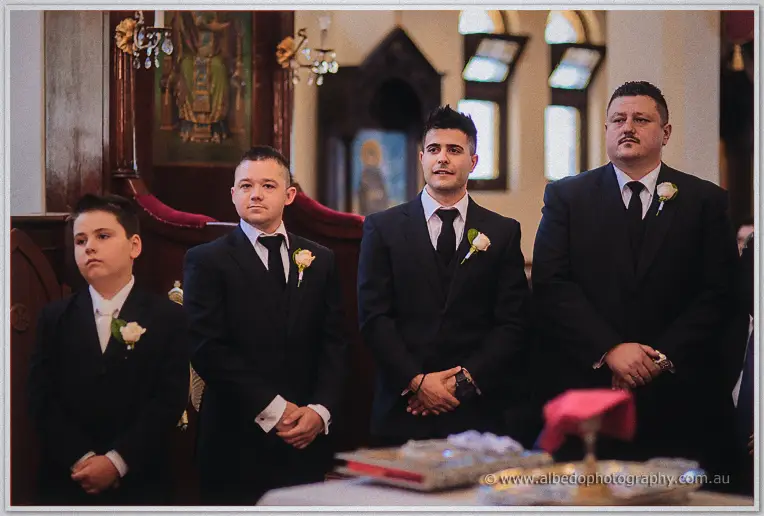 James and his groomsmen stand solemn with young attendants before the gilded icon screen