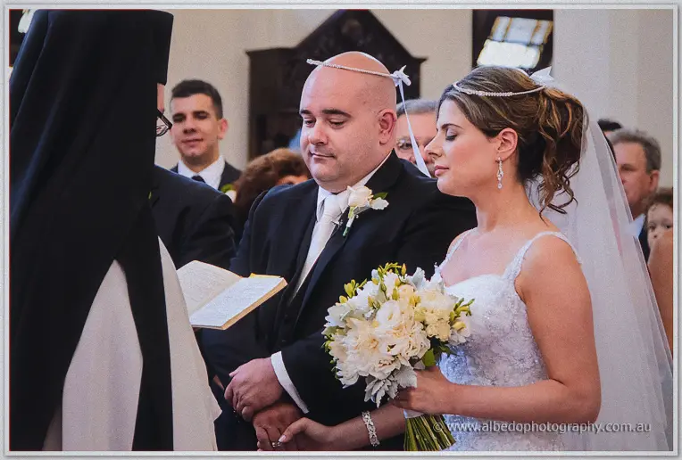 James and Elena wear pearl stefana crowns before the priest's open book
