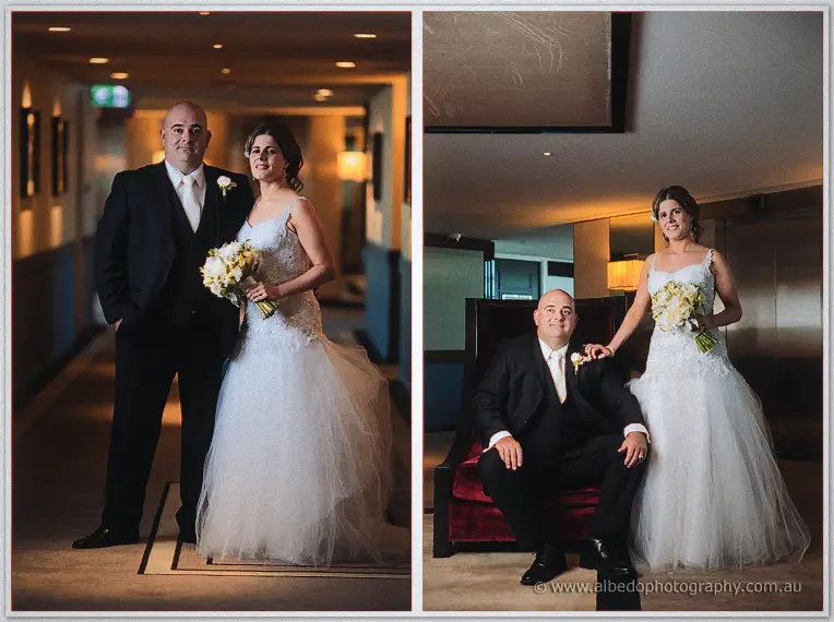 Elena rests her hand on James's shoulder as he sits in a red velvet chair in a warmly lit hotel lounge