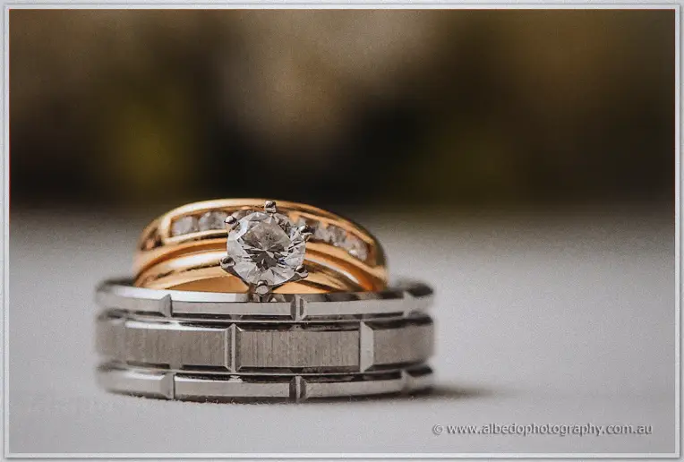 Macro close-up of a solitaire diamond ring resting on gold and engraved silver wedding bands