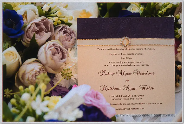 Close-up of Haley and Matt's invitation beside mauve roses, blue anemones and soft pastel blooms