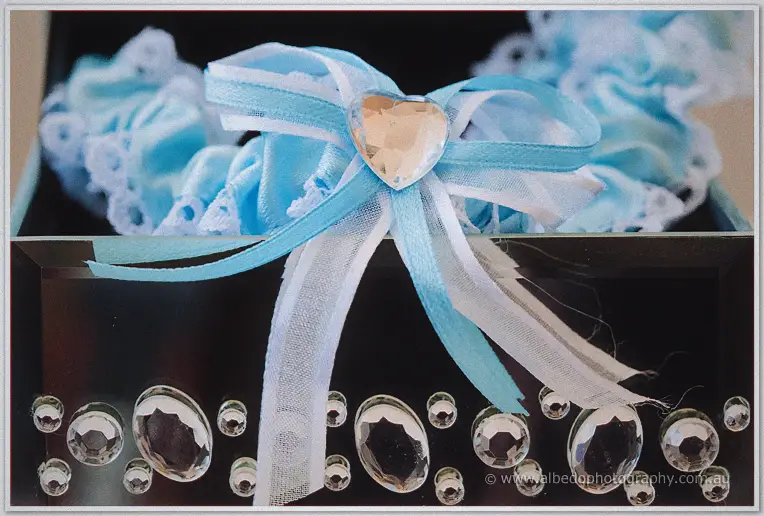 Haley's blue lace garter with ribbon bow and heart jewel rests on a crystal-studded box