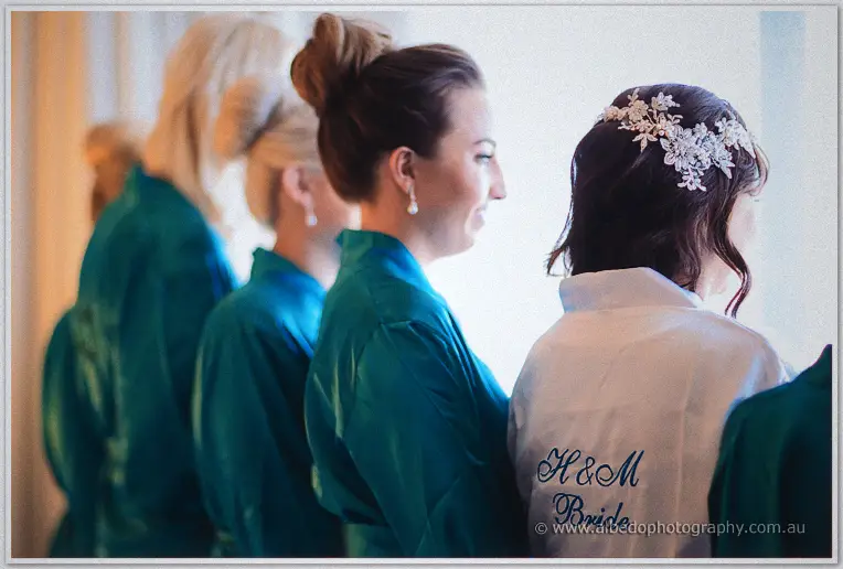 Haley's bridesmaids line up in teal robes behind her white H and M bride robe and floral headpiece