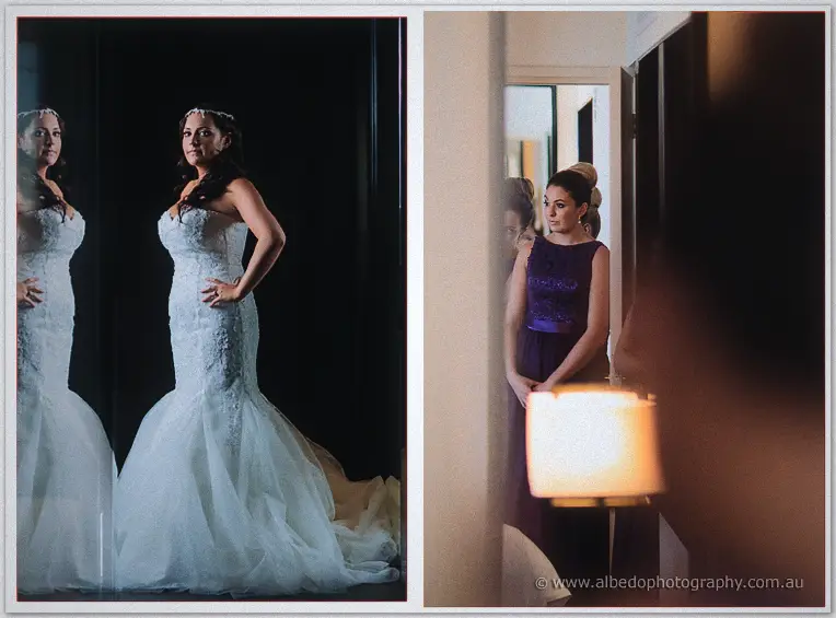 Haley poses by a dark mirror in her mermaid lace gown as a purple-clad bridesmaid waits at the lamplit doorway