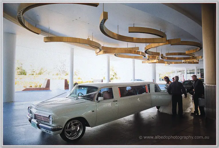 Haley steps from the white stretch limousine beneath sweeping golden swirls of the hotel portico