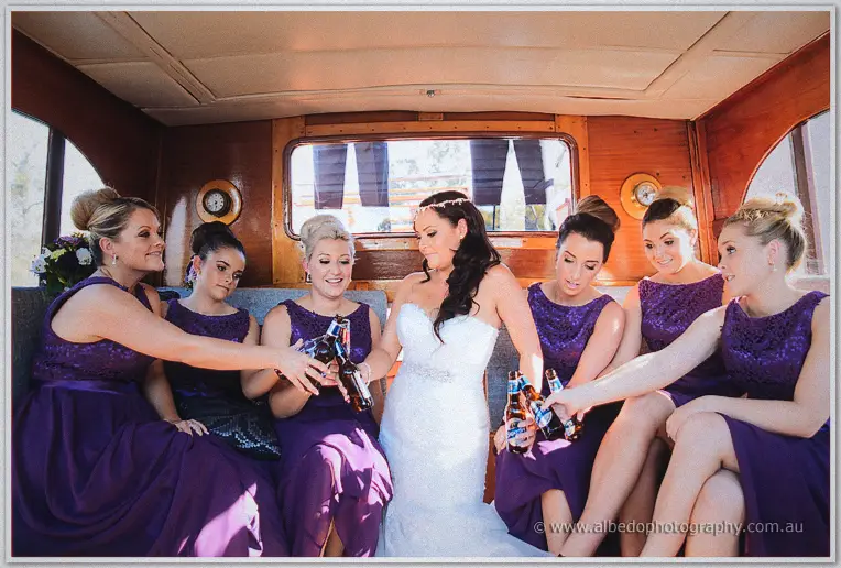 Haley and her bridesmaids clink beer bottles together in the cruiser's wooden cabin on the Swan River