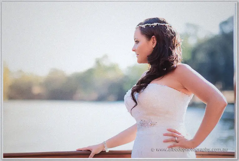 Haley gazes over the rail in profile as soft afternoon light falls across the river behind her