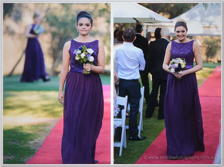 Bridesmaids in deep purple gowns walk the red carpet aisle one by one at the Caversham garden ceremony