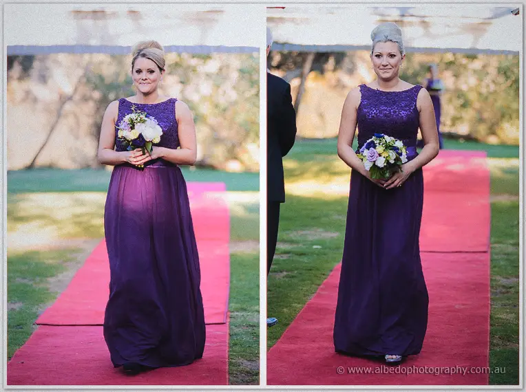 A blonde bridesmaid carries her white bouquet down the red carpet under warm late-afternoon sun