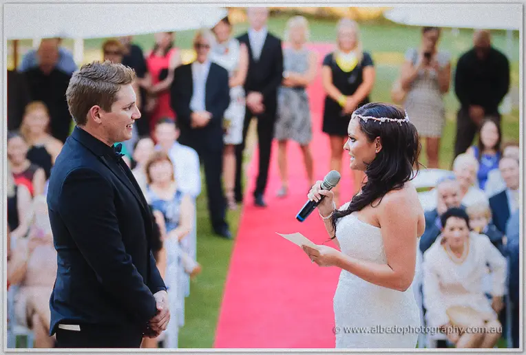 Haley smiles through her vows into the microphone as Matt listens on the red carpet aisle