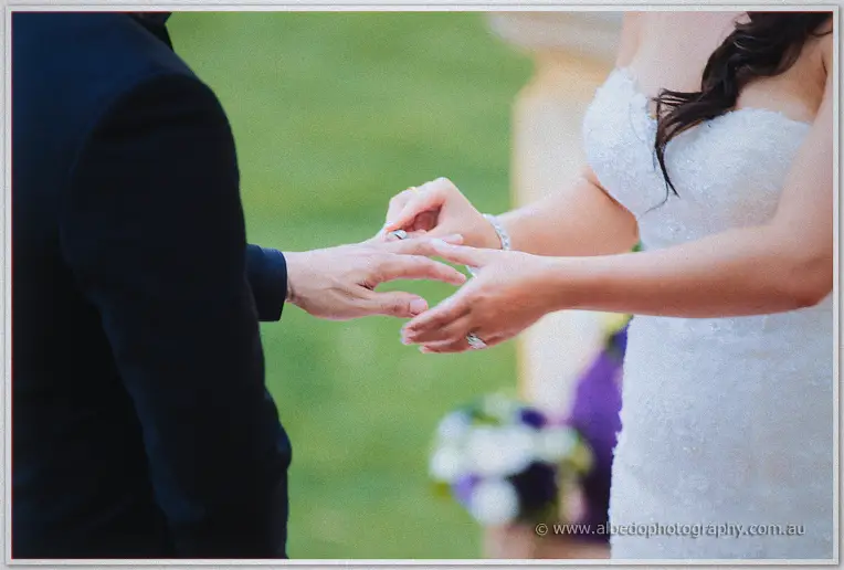 Haley slides the wedding ring onto Matt's finger in a close-up against soft green lawns
