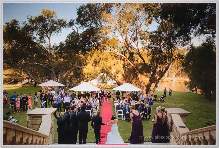 Newlyweds Haley and Matt walk back down the red carpet as guests cheer beneath riverside gums