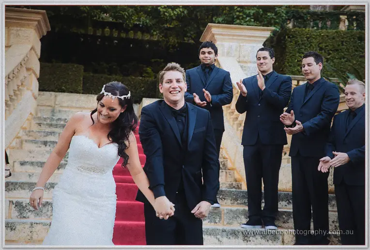 Haley and Matt laugh their way down the red-carpeted steps as groomsmen in navy suits applaud behind.