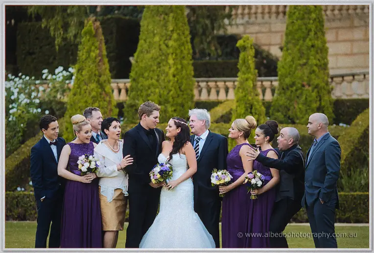 Haley and Matt share a look among bridesmaids in purple in the manicured hedges of the Caversham garden.
