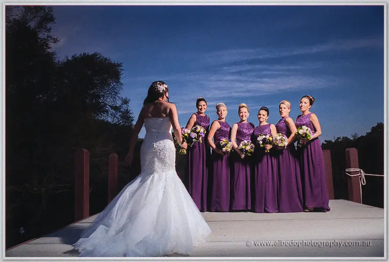 Haley joins her bridesmaids on the jetty, their purple gowns lit against a deep blue twilight sky.