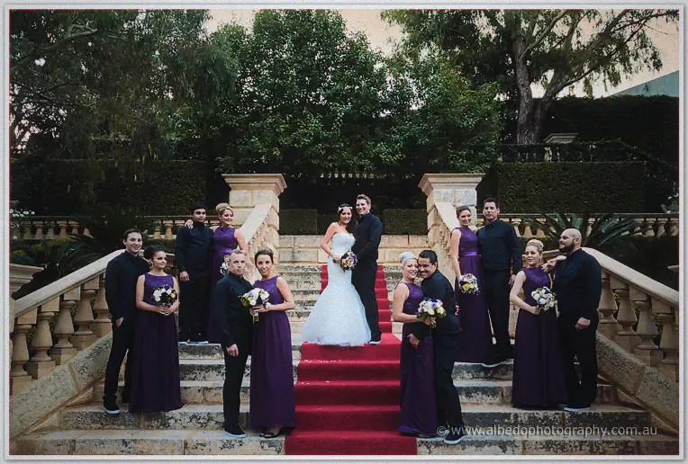The bridal party gathers on the red-carpeted stone staircase as Haley and Matt embrace at the top.