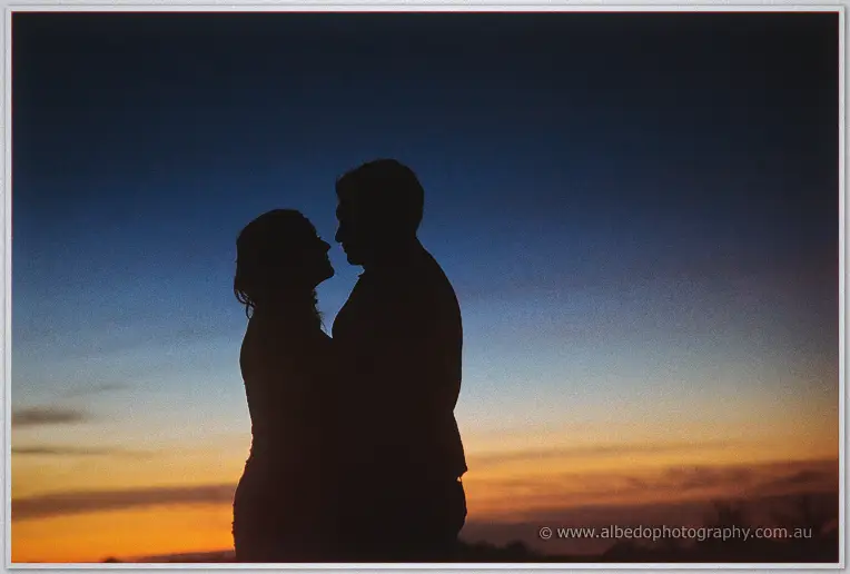 Haley and Matt are silhouetted nose to nose against a deep blue and orange dusk sky.