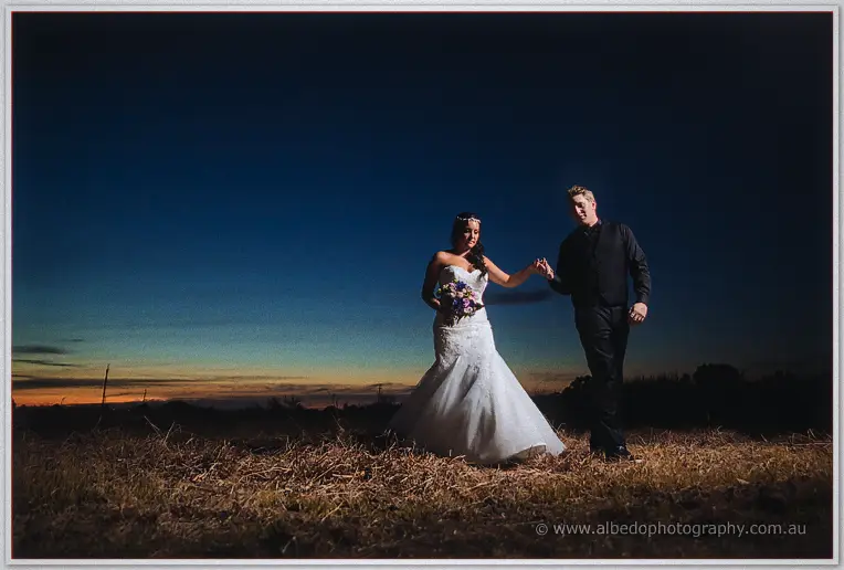 Haley leads Matt by the hand through the grassy field as night falls, lit softly against the darkening sky.