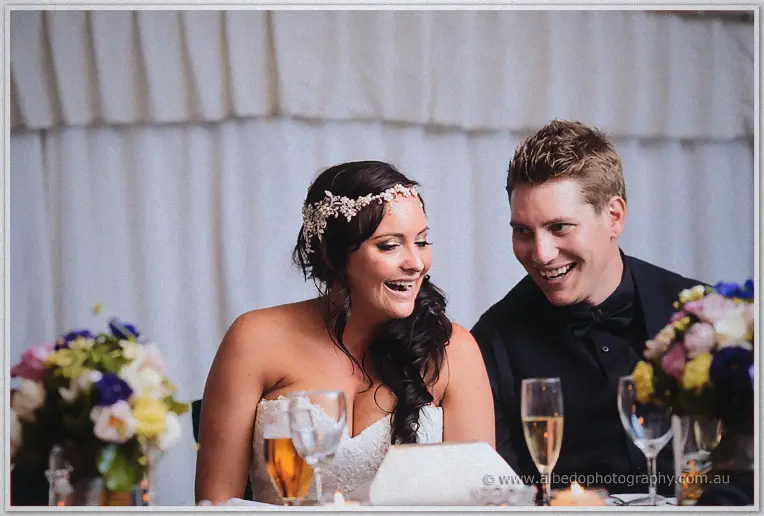 Haley and Matt laugh together at the head table, her beaded headpiece catching the marquee light.