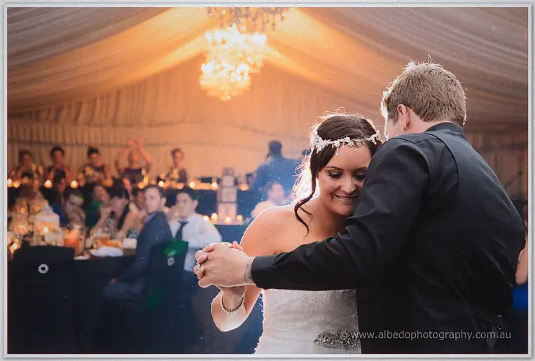 Haley and Matt forehead to forehead mid-dance, smiling under marquee chandeliers and candlelight