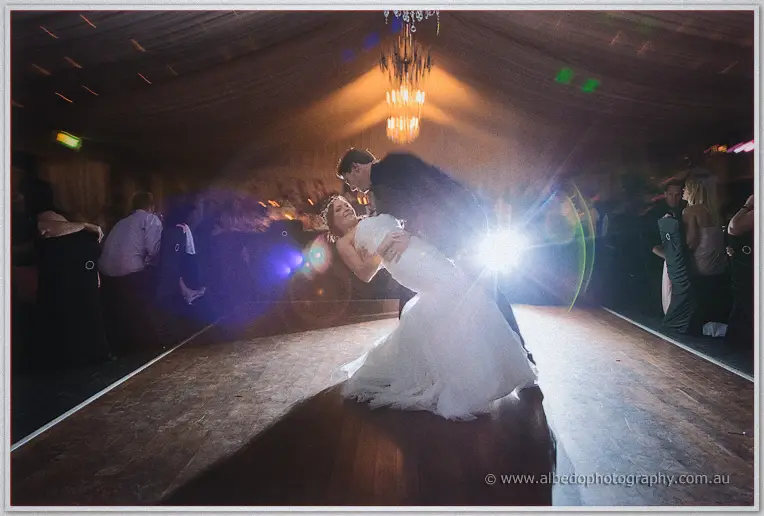 Matt dips Haley low across the dance floor in a backlit flare beneath the marquee chandelier