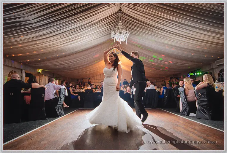 Wide view of Haley and Matt's first dance beneath a chandelier in the draped marquee at Caversham House