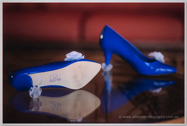 Vivid royal blue heels with crystal I Do soles and flower clips, mirrored on the dark table