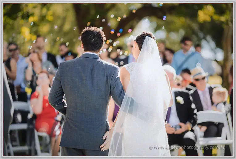 Hand in hand, the newlyweds walk back up the aisle through drifting bubbles.