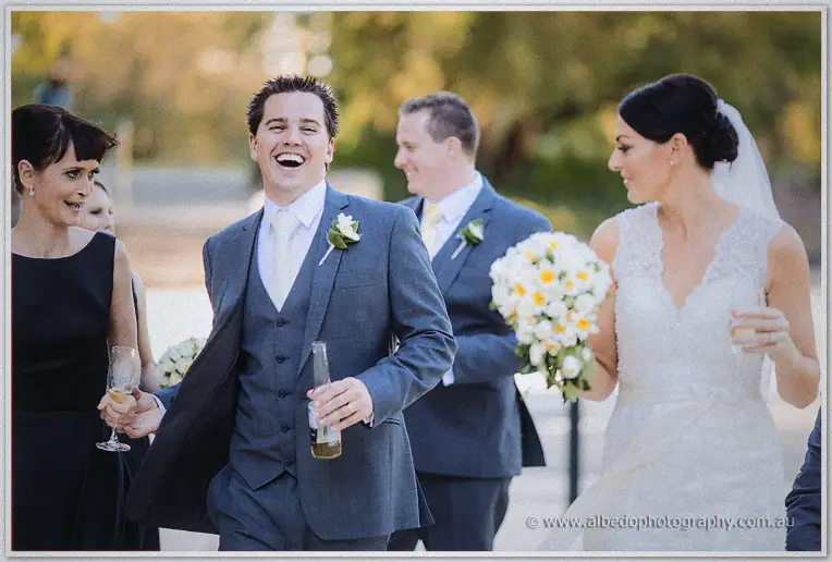 Nathain laughs mid-stride with a beer as Stacey carries her bouquet alongside.