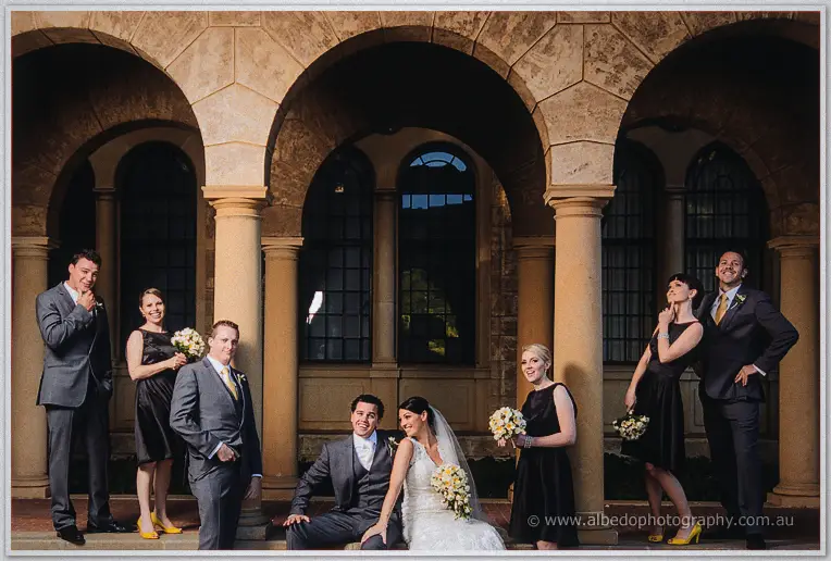 Bridal party lounges on the colonnade steps with yellow heels popping against dark dresses.