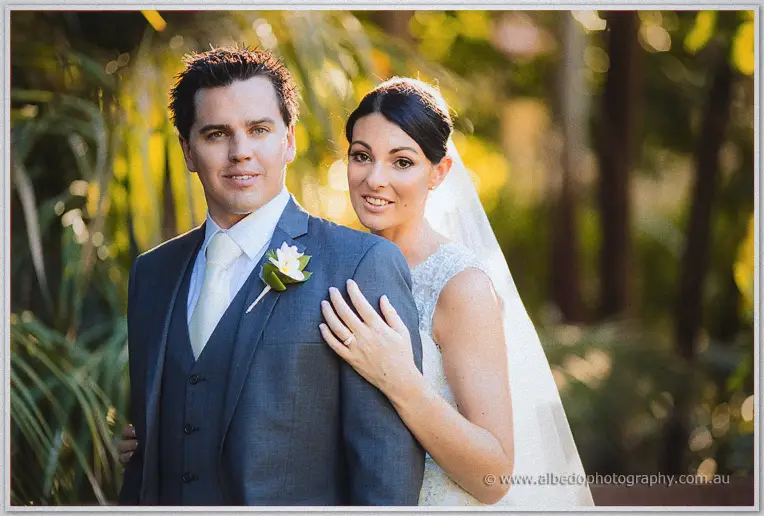 Stacey rests her hand on Nathain's shoulder as both look past the camera in golden light.