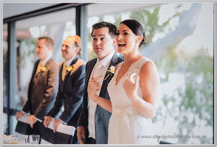 Mid-entrance the bride cracks up laughing while her groom pulls a wide-eyed face for guests.