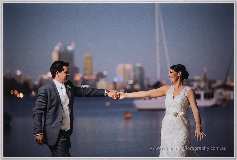 Laughing, he spins his bride out on the foreshore, Perth's glowing towers blurred across the bay.