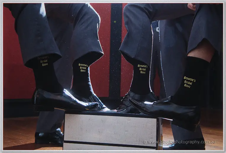 Close-up of the groomsmen's matching Brownie's Bridal Boyz socks above polished black shoes.