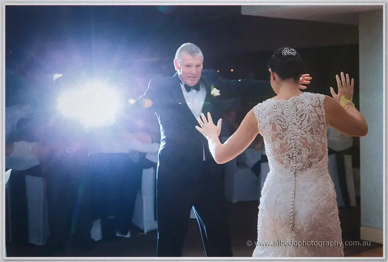 Stacey and her father spin arm in arm on the dance floor, bathed in a bright lens flare.