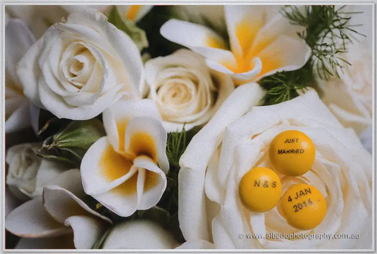 White roses and frangipani from Stacey's bouquet cradle yellow sweets marked Just Makried, 4 Jan 2014.