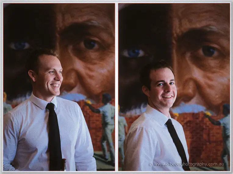Two grinning groomsmen, one with a beer bottle, posed before the painted mural portrait at home
