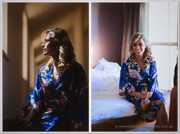 Cristina in a blue floral robe, hair curled, smiles by the hotel window before dressing
