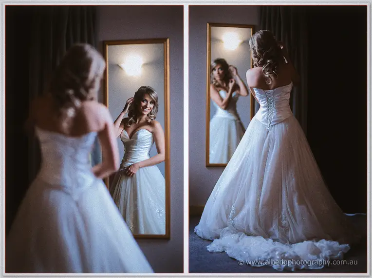 Cristina checks her reflection in the mirror, dress train pooling on the carpet