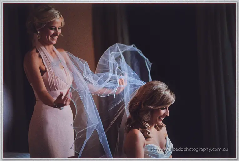 A bridesmaid lifts Cristina's billowing veil as they laugh together