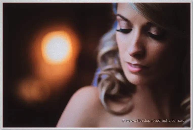 Intimate close-up of Cristina's downcast lashes against warm window bokeh