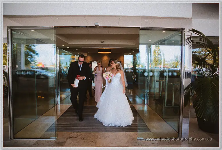 Cristina and her father step through the hotel's glass doors toward the waiting limousine