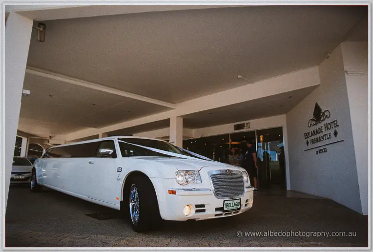 White stretch limousine with bridal ribbon parked under the Esplanade Hotel portico
