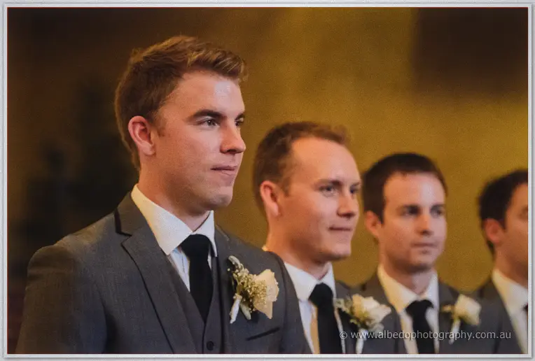 Mitch waits at the altar with his groomsmen in grey suits and white boutonnieres