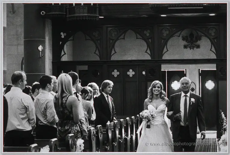 Guests turn to watch Cristina and her father walk the aisle beneath carved gothic arches at St Patrick's
